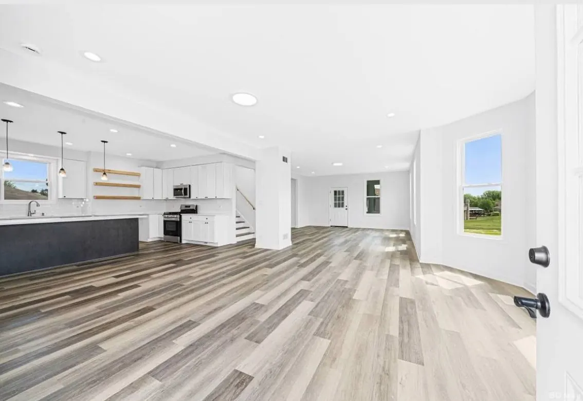 Bright open-concept living space with modern kitchen and wood-tone flooring